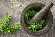 Close-up of fresh rosemary sprigs in a stone mortar and pestle, highlighting natural herbs.