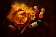 Top view of turmeric powder, curcuma roots, and essential oil on wooden surface.