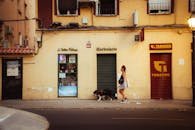 Urban scene in Madrid showing a woman walking past storefronts with her dog.