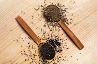 Flat lay of black sesame and caraway seeds on wooden spoons, showcasing culinary ingredients.