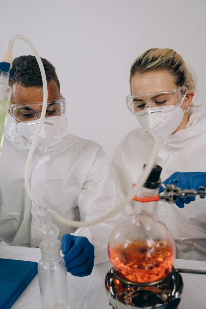 Two scientists in protective gear work on an experiment in a laboratory setting.