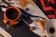 Top view of Mexican cafe de olla with cinnamon sticks, chocolate, and coffee beans on a rustic table.