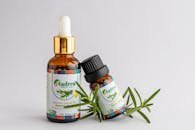 Close-up of rosemary essential oil bottles with fresh rosemary sprig, offering natural aromatic healing.