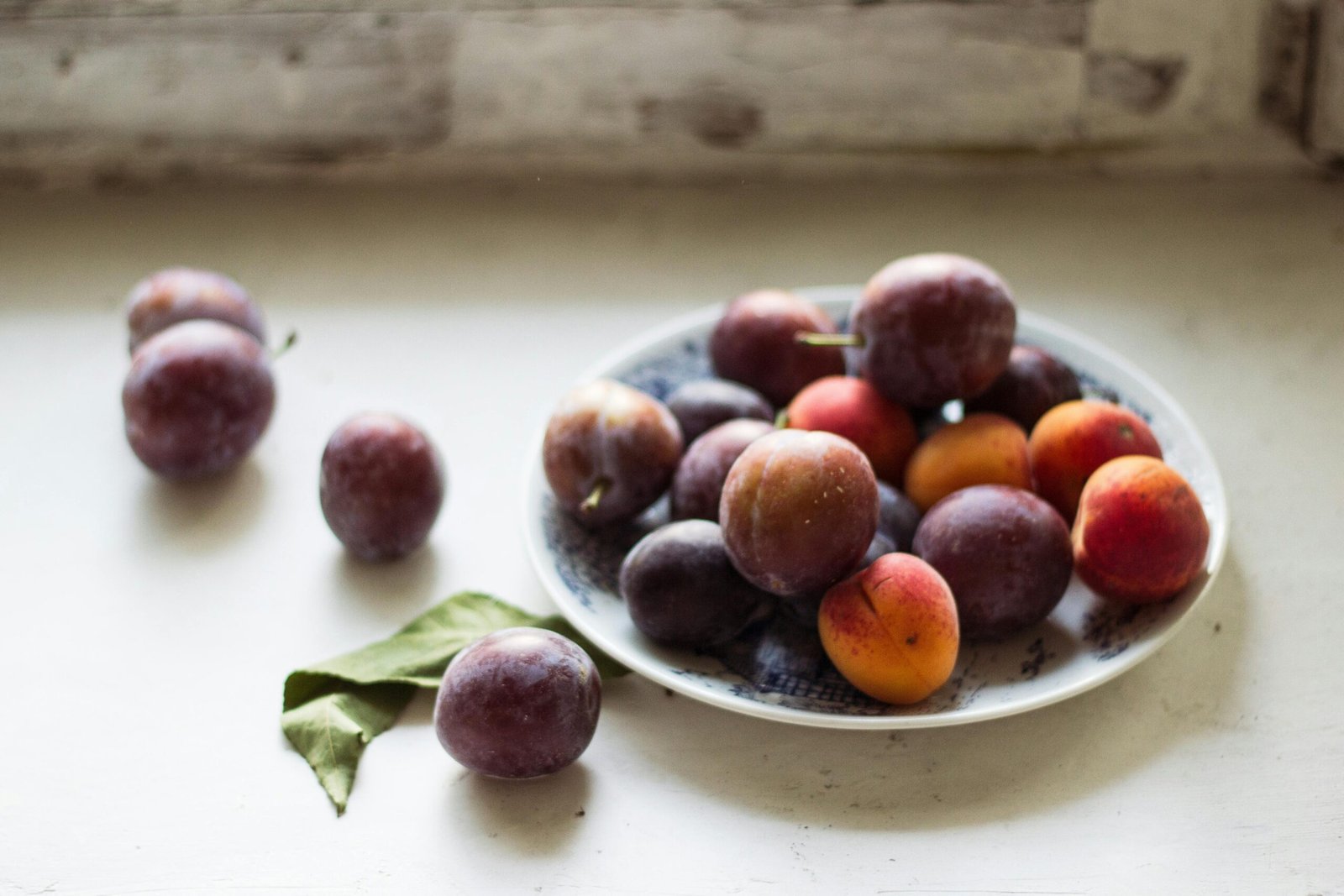 Vibrant plums arranged on a plate, capturing raw and natural beauty.