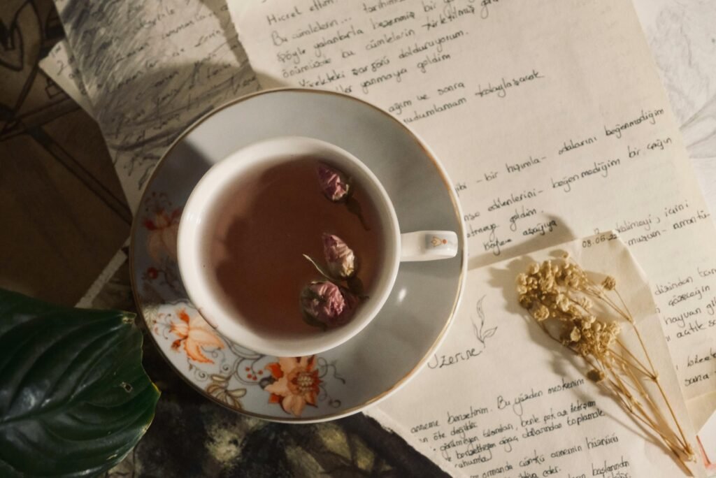 Aesthetic tea setup with floral cup, dried roses, and handwritten notes for a serene vibe.
