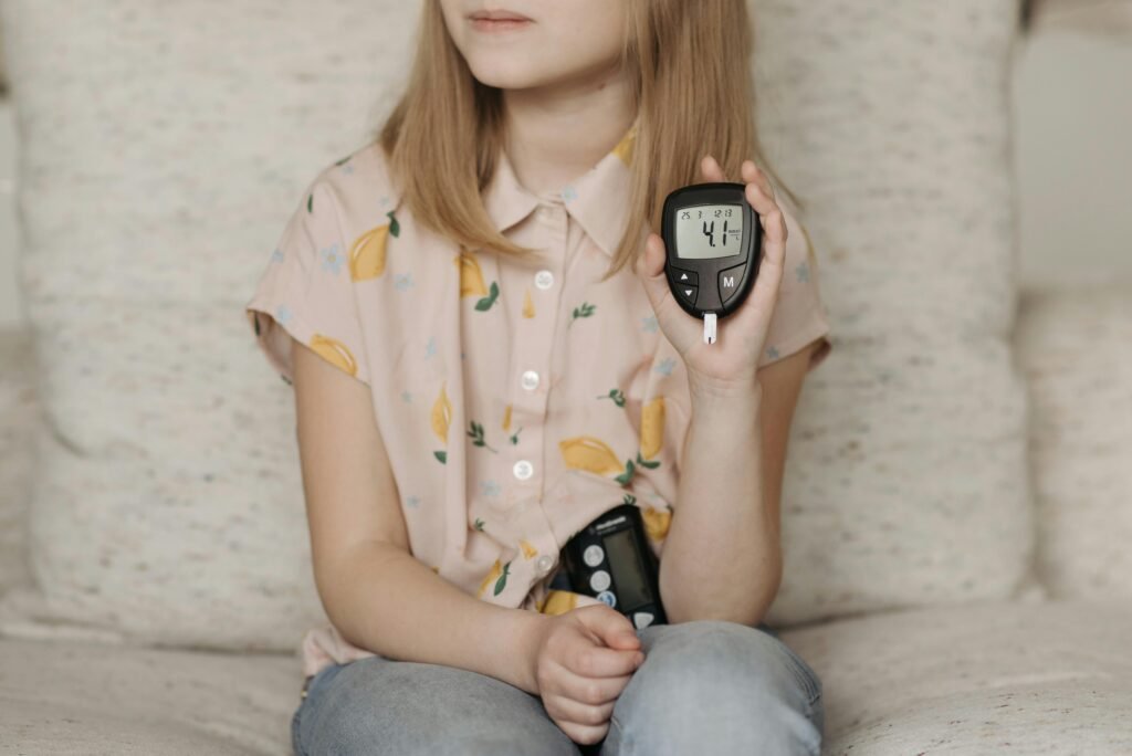 A young girl sitting at home using a glucometer to monitor her blood sugar levels, illustrating diabetes management.