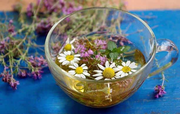 Remedio casero para la ansiedad y el estrés: infusión de melisa, manzanilla y lavanda sobre mesa de madera con luz cálida nocturna