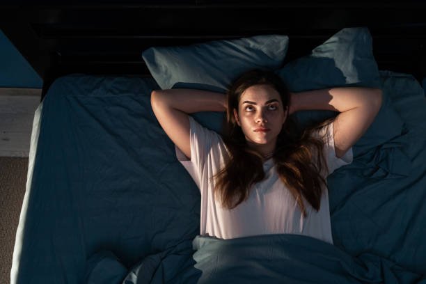 Insomnio de mantenimiento: despertares nocturnos frecuentes Mujer despierta de madrugada en la cama por insomnio de mantenimiento, mirando el techo sin poder volver a dormir
